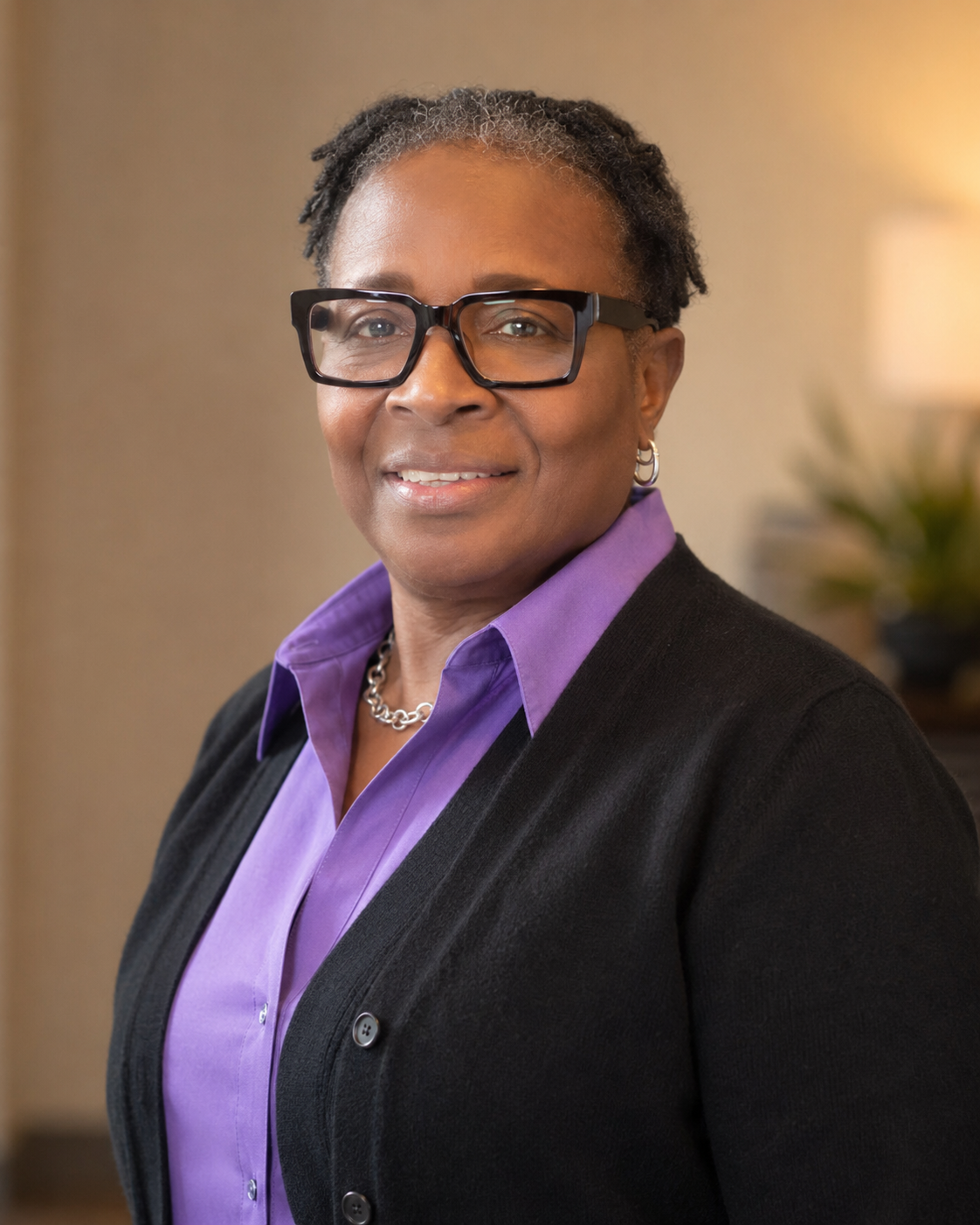 Woman in a purple shirt and black cardigan.